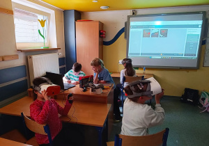 Uczniowie klas młodszych wędrują przy użyciu okularów VR z kropelkami po cyklu wodnym.