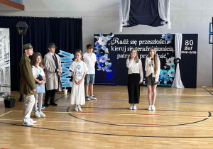 Część artystyczna Jubileuszu – występ uczniów. W tle dekoracja nawiązująca do historii szkoły i postaci patrona Aleksandra Kamińskiego