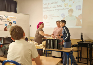 Uczestnicy konkursu informatycznego odbierają nagrody od organizatorów.