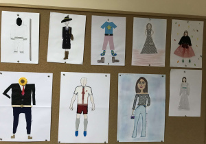 Tablica na szkolnym korytarzu z zamieszczonym pracami uczniów klas piątych. Projekty strojów wykonane na technice.