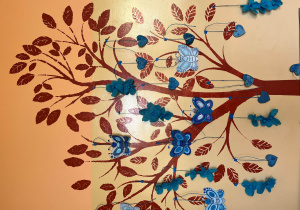 Papierowe motyle w kolorze niebieskim przyklejone do drzewa namalowanego na ścianie