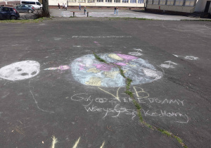 Rysunek i hasło promujące ochronę Ziemi wykonane kredą przez uczniów z klasy 5b na boisku szkolnym – Gdy o Ziemię dbamy wszyscy się kochamy