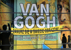 Plakat zamieszczony przed wejściem do hali wystawowej informujący o wystawie multisensorycznej – Zanurz się w świecie obrazów