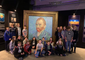 Zdjęcie grupowe uczniów klasy 6b stojących przed autoportretem Vincenta van Gogha