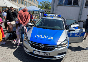 Policyjne stanowisko – radiowóz, policjanci z broszurami i odblaskami