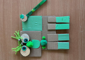 Zielony stworek z materiałów sztucznych, drewnianych i papierowych