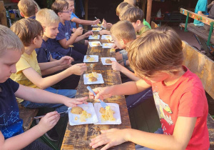 Uczniowie jedzą na wozach konnych ziemniaki i kiszoną kapustę
