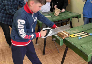 Uczniowie tną kawałki drewna za pomocą piły ręcznej