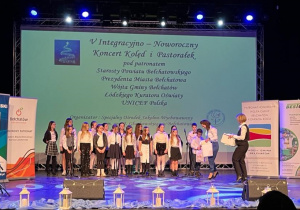 Organizatorzy Integracyjno-Noworocznego Koncertu Kolęd i Pastorałek wręczają uczestnikom podziękowania za udział w wydarzeniu.