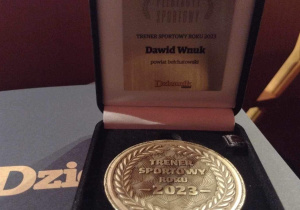 Medal Trenera Sportowego Roku 2023 dla pana Dawida Wnuka umieszczony w drewnianym etui.