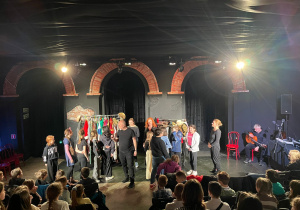 Grupa uczniów i aktorów na scenie podczas trwania spektaklu
