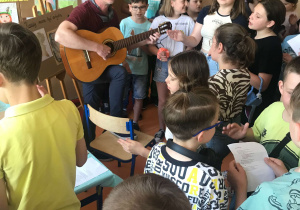Zabawy ze śpiewem na szkolnym korytarzu. Wspólne śpiewanie piosenek. Nauczyciele grają na gitarze.