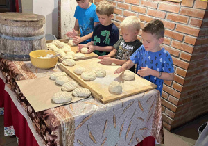 Uczniowie wygniatają ciasto i formują chlebki.