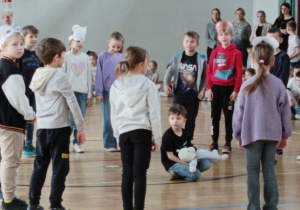 Uczniowie klasy 1a w opaskach z niedźwiedziami wykonują pląś „Niedźwiadek”.