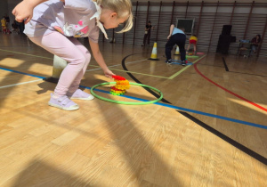 Przedszkolaki rywalizują miedzy sobą przenosząc klocki i zostawiając je w kole.