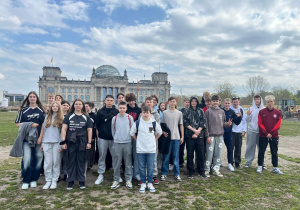 Uczestnicy wycieczki do Berlina stoją przed gmachem Reichstagu.