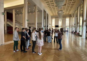 Uczniowie klasy 7c z oprowadzającą przebywają w foyer z weneckimi lustrami.