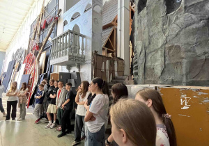 Oprowadzająca rozmawia z uczniami o rekwizytach i specyfice pracy w Teatrze Wielkim.