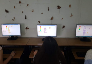 Informatyka. Programowanie sygnalizacji świetlnej, bezpieczna droga do szkoły. Prace uczniów klas 5b i 7a widoczne na ekranach komputerów.