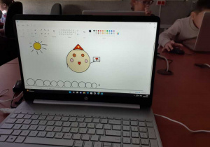 Informatyka. Prace uczniów klas młodszych widoczne na ekranach komputerów