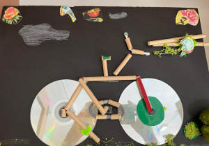 Rower - Praca wykonana na kole plastycznym przez uczniów klas piątych z zastosowaniem płyt CD, plastikowych rurek i materiałów dekoracyjnych.