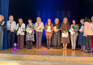 Nauczyciele stojący na scenie podczas odbierania nagróg