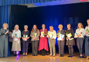 Nauczyciele stojący na scenie podczas odbierania nagróg