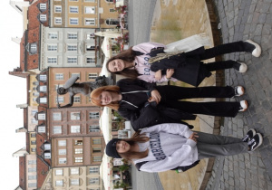 Trzy uczennice z klasy 8f stoją przy pomniku Warszawskiej Syrenki na Starym Mieście