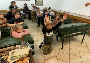 Uczeń siedzi w ławce słuchając o tym jaki kary wymierzane były dawniej w szkole. Symulowanie klęczenia na grochu.