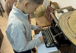 Uczeń klasy 2d pisze na maszynie do pisania.