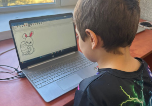 Uczeń klasy 2b pracuje w programie graficznym Paint tworząc motywy wielkanocne.