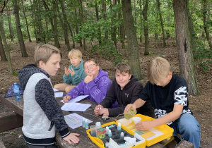 Uczniowie wykonują test na obecność amoniaku w wodzie ze stawu.