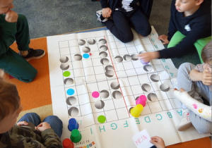 Uczniowie przygotowali grę na macie dom kodowania i grają w nią.