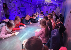 Dzieci wykonują świąteczne prace plastyczne podczas warsztatów.