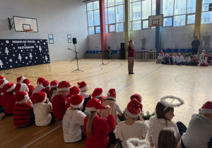 Uczniowie zebrani na sali gimnastycznej słuchają Pani dyrektor Joanny Mrowińskiej Wange