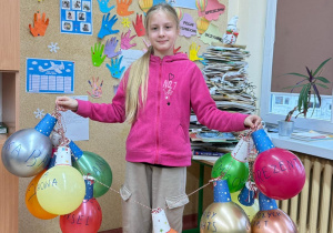 Uczennica klasy 4c stoi z pracą konkursową wykonaną z balonów.