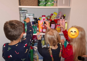 Wychowankowie Domu Dziecka układają kosmetyki na półkach.