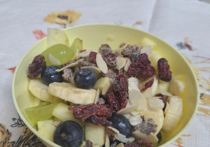 Miska ze zdrowymi przekąskami -bananami, rodzynkami, borówkami, płatkami.