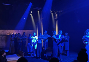 Wszyscy aktorzy tańczą na scenie przed zgromadzoną widownią.