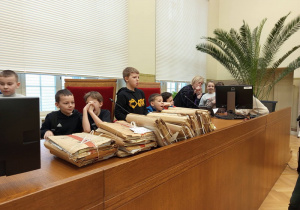 Uczniowie siedzą za stołem sędziowskim.