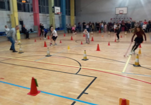 Każda z drużyn pokonuje slalom między pachołkami , prowadząc piłkę kijem do unihokeja.