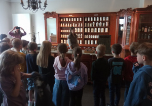 Pierwszaki oglądają stare wagi apteczne, oglądają naczynia, w których przechowywano lekarstwa. Farmaceuta opowiada im o tym jak wyglądał ten zawód dawniej