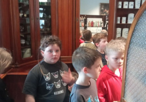 Pierwszaki oglądają stare wagi apteczne, oglądają naczynia, w których przechowywano lekarstwa. Farmaceuta opowiada im o tym jak wyglądał ten zawód dawniej