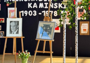 Dekoracja poświęcona pamięci Aleksandra Kamińskiego – tablica z pracami uczniów, wierzby, sztaluga z portretem Aleksandra Kamińskiego i sztaluga z Krzyżem harcerskim