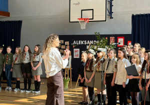 Pani Magdalena Kieszek dyryguje szkolnym chórem podczas uroczystości.