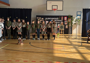 Apel z okazji Święta Patrona Szkoły – uczniowie i nauczyciele zgromadzeni na sali gimnastycznej.