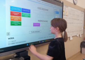 Uczniowie rozwiązują na tablicy multimedialnej zadania związane z wodą