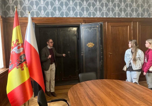 Pracownik kancelarii prezentuje uczniom zabytkowy sejf.