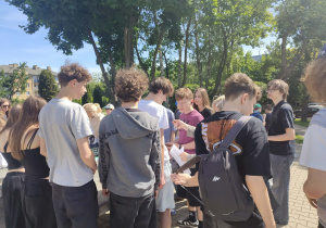 Uczniowie klas ósmych wykonują zadania matematyczne podczas gry terenowej