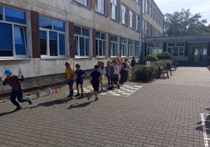 Zawody klas młodszych na szkolnym boisku – wyścigi z butelkami.